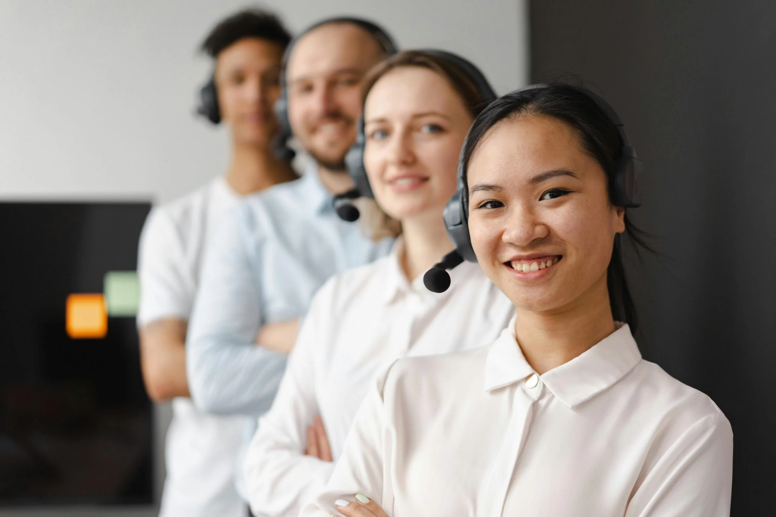 Trabajadores en un call center con auriculares y micrófono, listos para responder preguntas de clientes